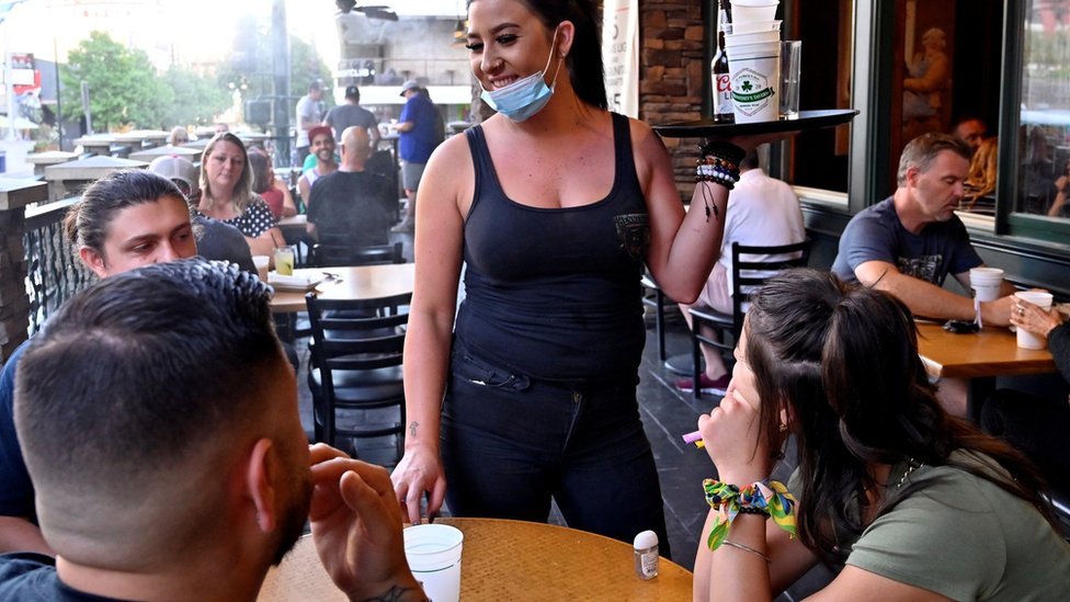 Waitress serves customers while masked